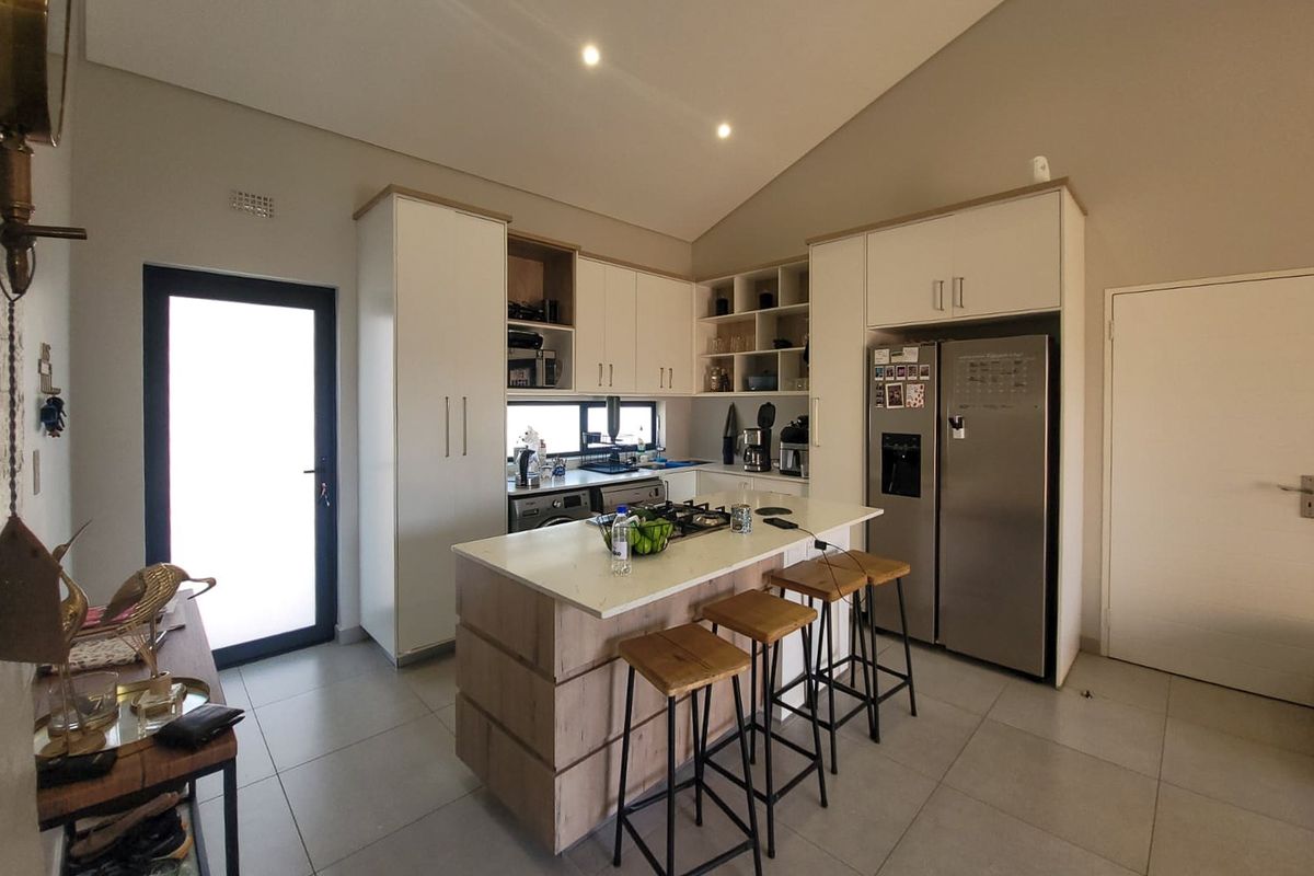 Modern kitchen featuring a central island with a gas hob, stone countertops, ample built-in cabinetry, and a high vaulted ceiling with recessed lighting.