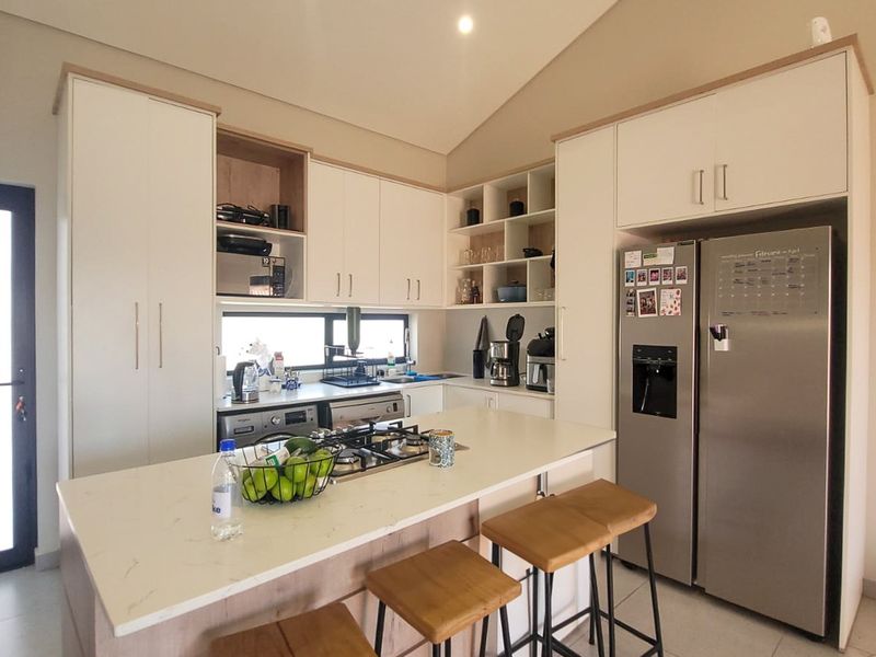 Modern kitchen featuring light wood and white cabinetry, stone countertops, a central island with a gas hob, and recessed lighting.