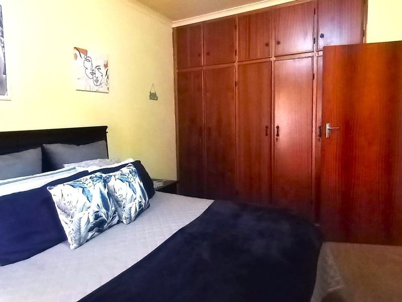 A bedroom featuring extensive floor-to-ceiling built-in wooden cupboards and a standard wooden door, offering functional storage space.
