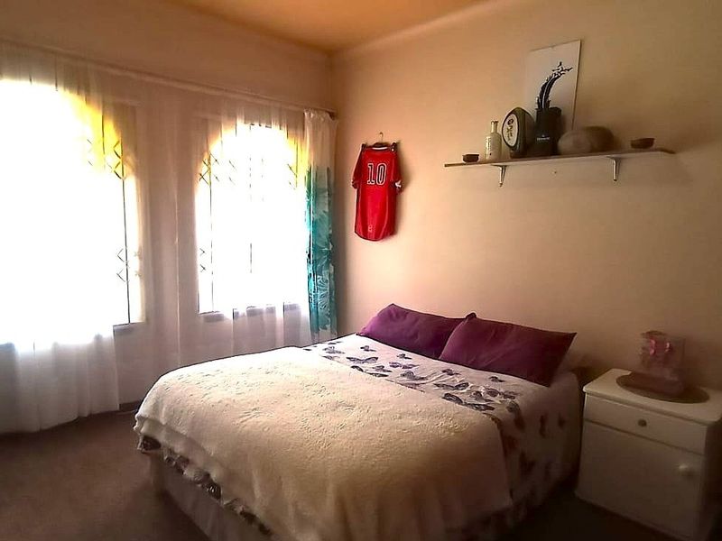A bedroom featuring arched windows that allow natural light, complemented by built-in wall shelving.