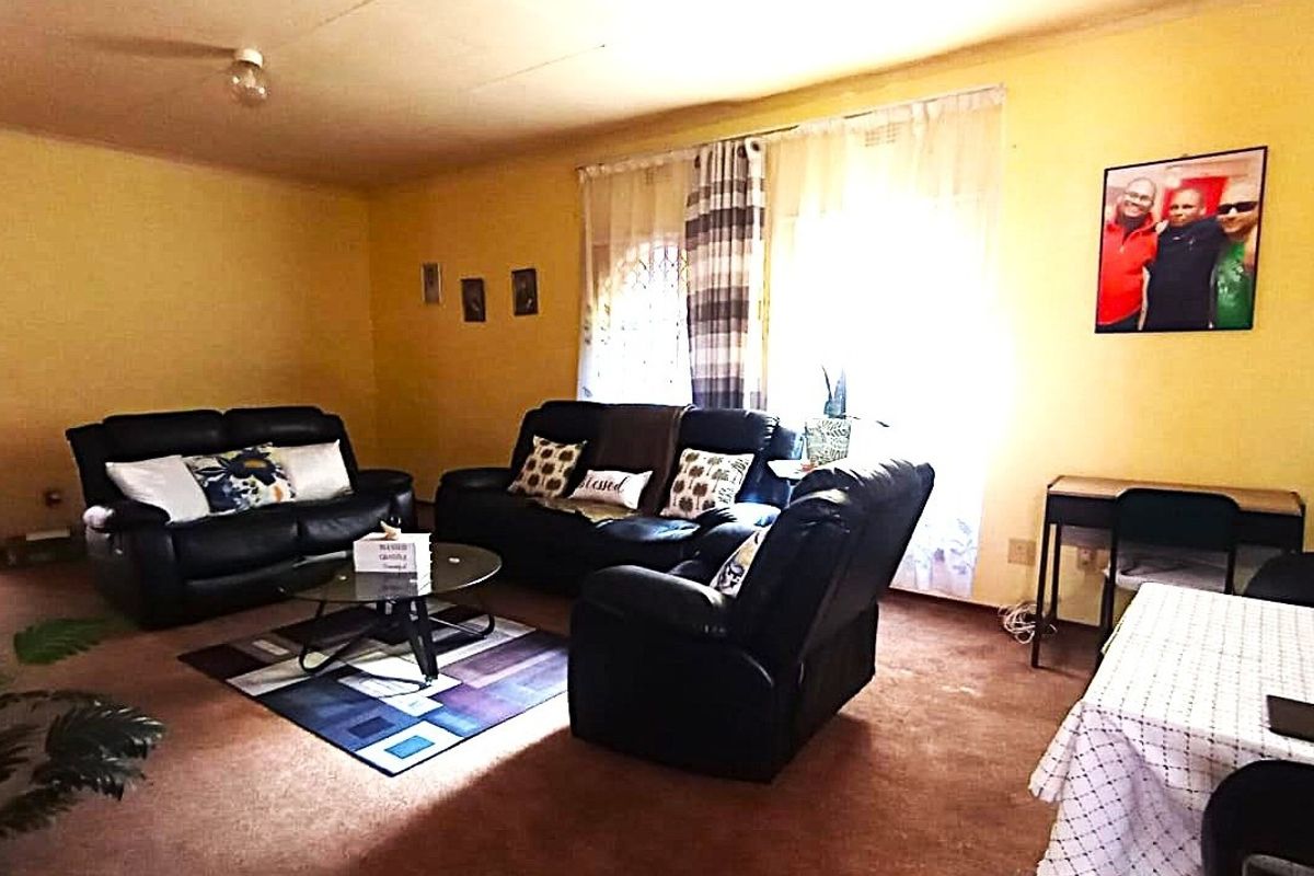 A spacious living room featuring carpeted flooring and large windows, offering a blank canvas for potential modernization and interior updates.