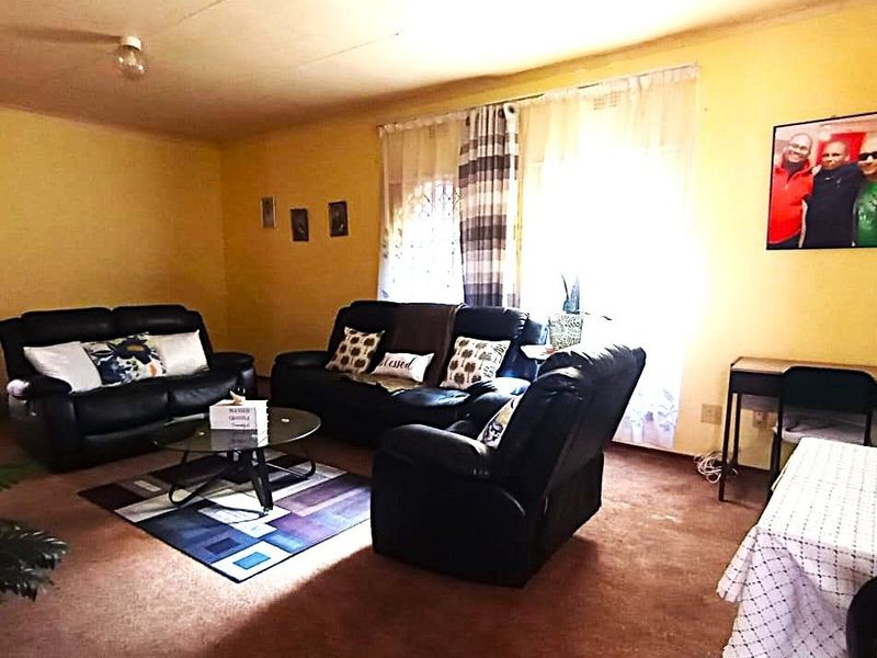 A spacious living room featuring carpeted flooring and large windows, offering a blank canvas for potential modernization and interior updates.