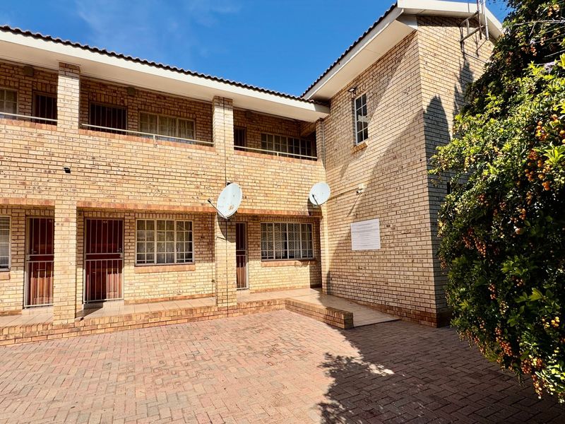A view of the rear exterior of the apartment complex, featuring a paved courtyard, face brick facade, and balcony access.