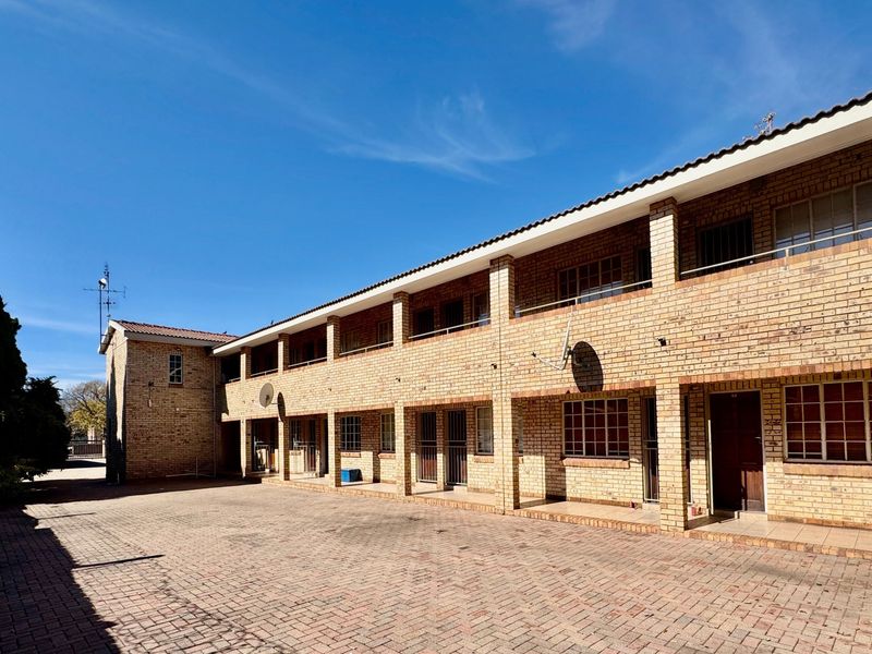 Exterior view of a multi-story apartment complex featuring face brick construction, paved driveway, and balcony access for upper-level units.