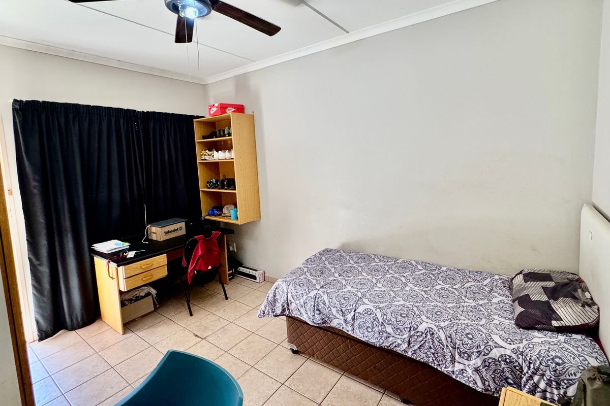 A functional bedroom featuring tiled flooring and a ceiling fan, providing a neutral space ready for personalization.