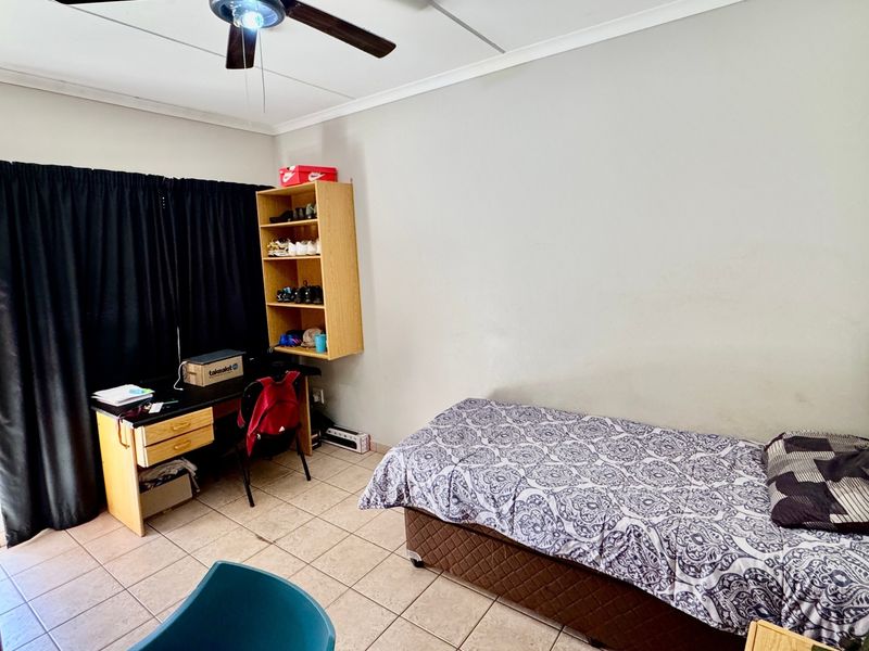 A functional bedroom featuring tiled flooring and a ceiling fan, providing a neutral space ready for personalization.