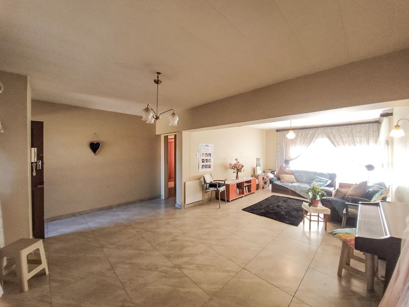Spacious open-plan living area featuring neutral tiled flooring and ample natural light, providing a versatile layout for dining and lounge arrangements.