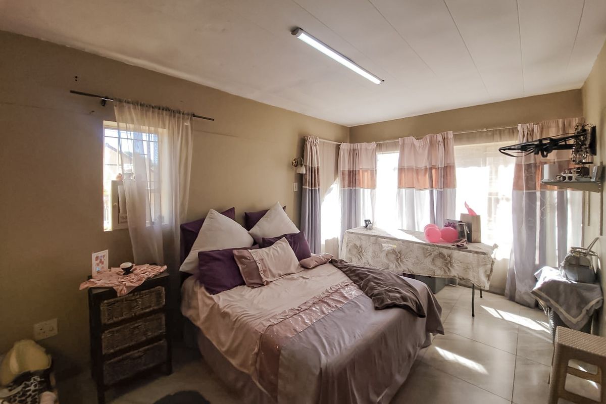A bedroom featuring tiled flooring and basic lighting, currently showing signs of wear on the ceiling and walls.