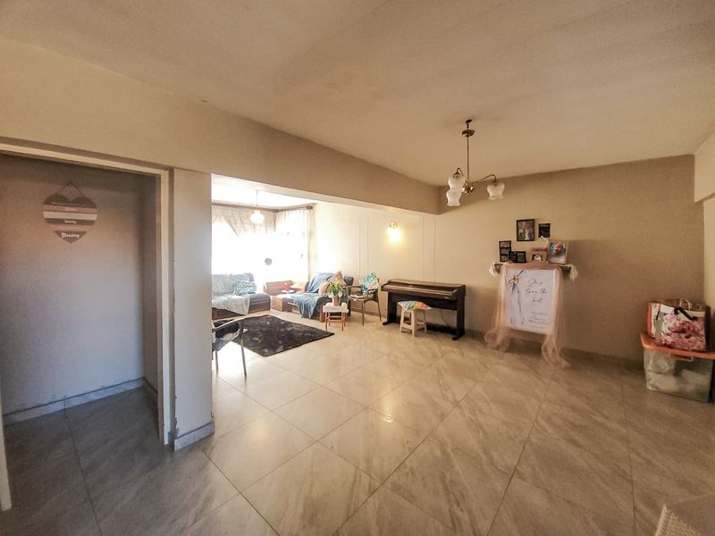 Spacious living area featuring neutral tiled flooring and integrated lighting, offering a versatile open-plan layout suitable for various furniture arrangements.