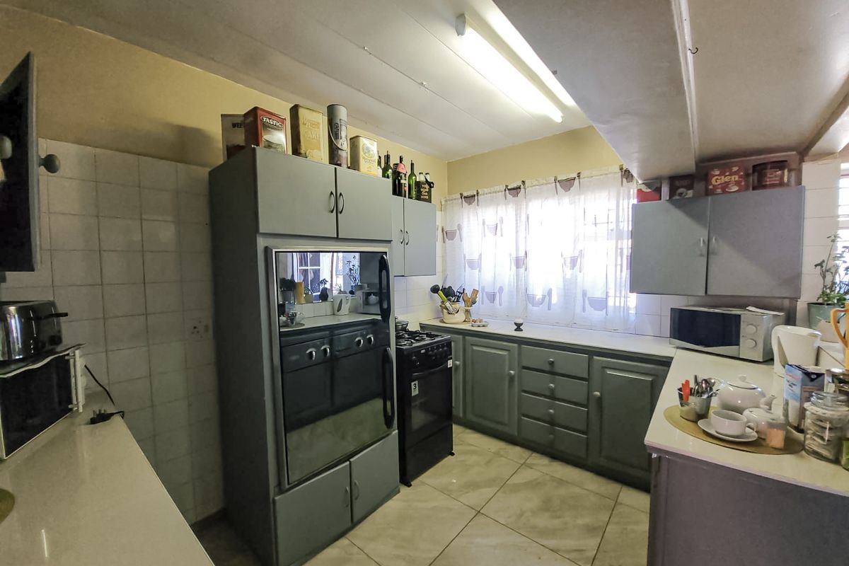 A functional kitchen featuring built-in cabinetry, tiled flooring, and a freestanding oven, offering a practical layout with potential for modern cosmetic updates.