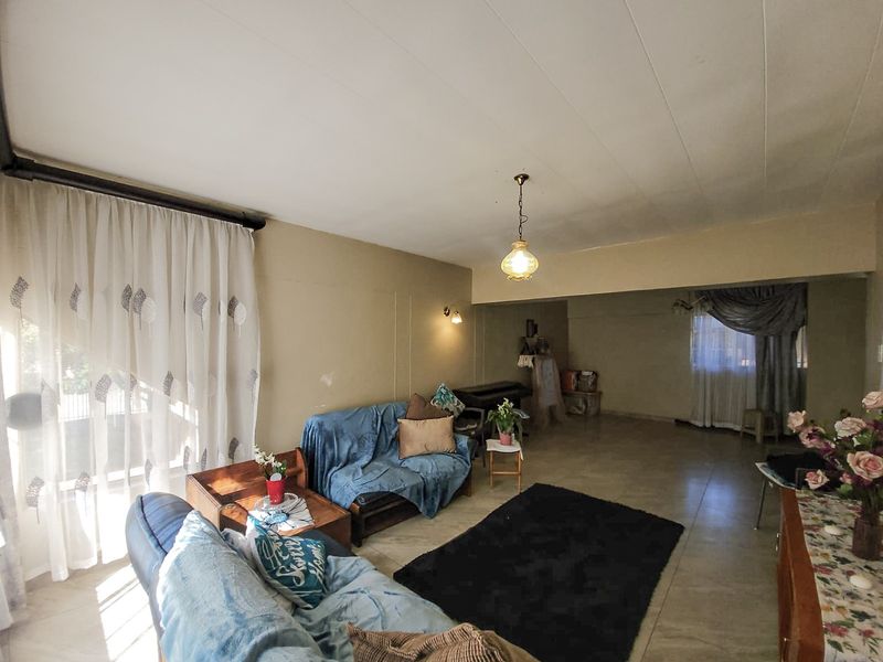 Spacious living area featuring tiled flooring, neutral wall tones, and natural light through large windows, offering a versatile layout for comfortable family living.