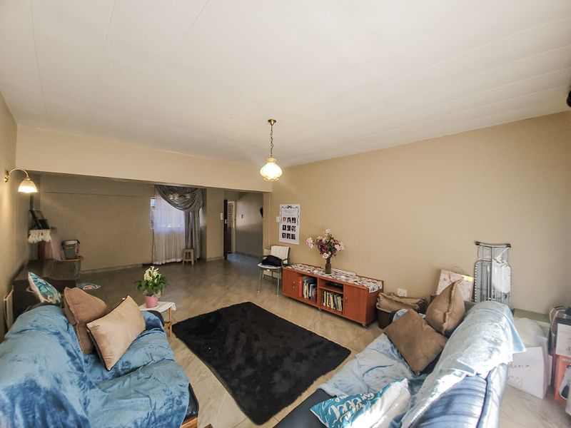 Spacious living room featuring neutral wall tones, tiled flooring, and classic pendant lighting, offering a versatile layout for comfortable family living.