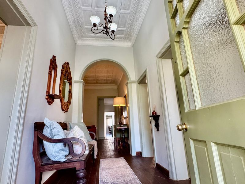 A character-filled hallway featuring original pressed metal ceilings, polished timber flooring, and an elegant archway leading through the home.