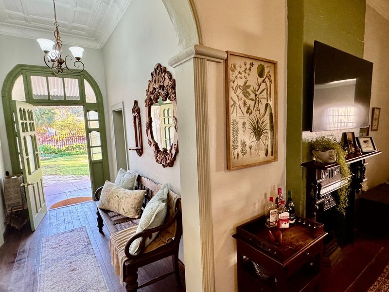 Welcoming entrance hall featuring an ornate ceiling, timber flooring, and a classic archway leading into the living area with a fireplace mantel.