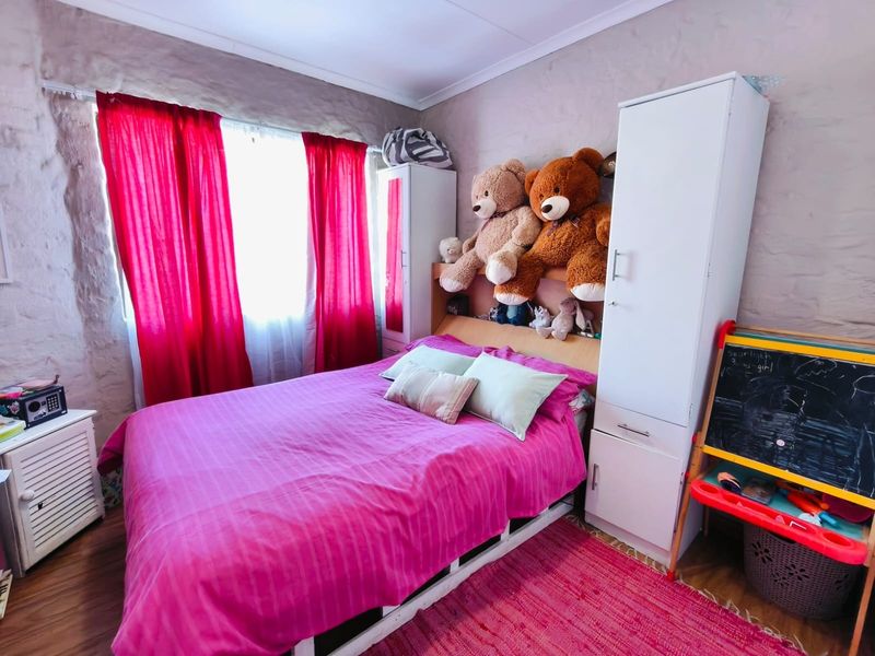 A bedroom featuring textured stone walls and laminate flooring, providing a cozy and characterful space.