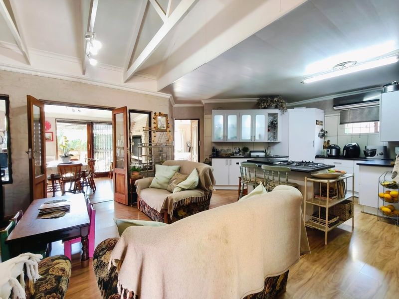 Open-plan living and kitchen area featuring vaulted ceilings with exposed rafters, laminate flooring, and a functional kitchen layout with built-in cabinetry and gas hob.