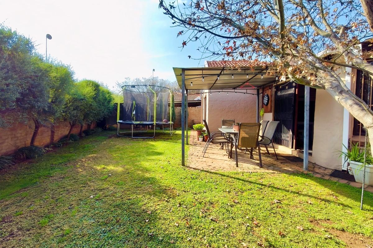 Rear garden area featuring a covered patio with paved flooring, a lawn, and secure boundary walling.