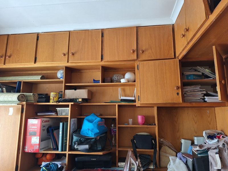 A bedroom featuring extensive built-in wooden cabinetry and overhead storage units, providing significant wall-to-wall shelving and cupboard space.