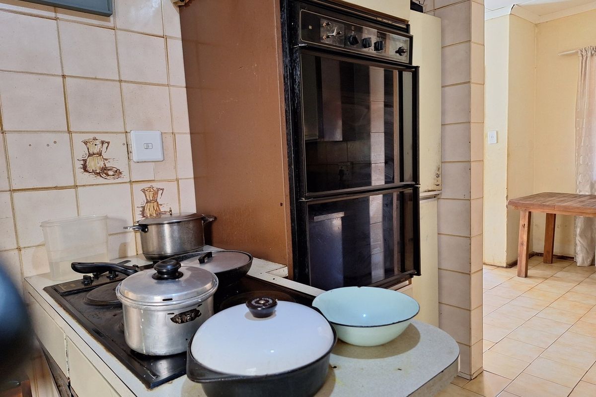A dated kitchen featuring a built-in oven, electric hob, and tiled backsplash, offering potential for a modern renovation.