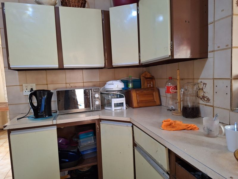 A dated kitchen featuring original laminate cabinetry, tiled splashbacks, and laminate countertops, offering significant potential for a modern renovation or cosmetic update.