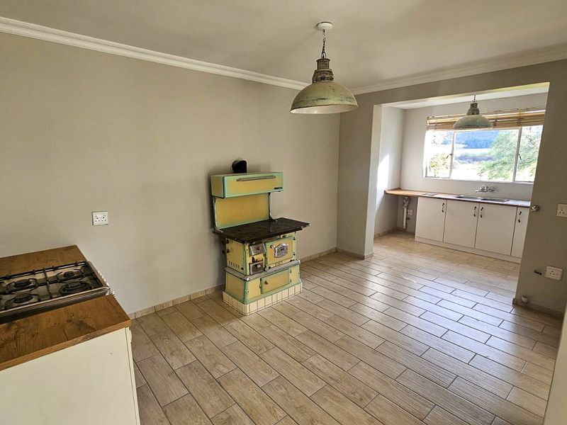 Spacious kitchen featuring a vintage stove, gas hob, built-in cabinetry, and tiled flooring with natural light from a rear window.