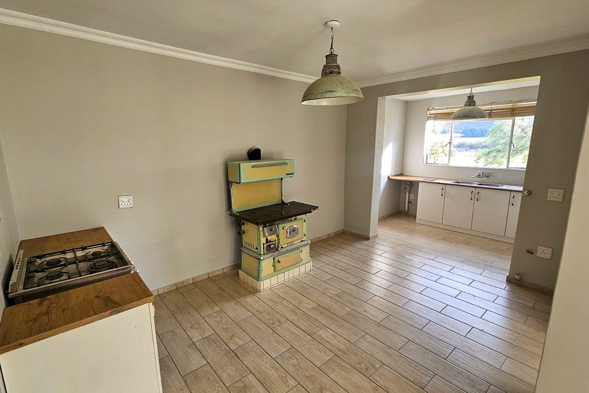 Spacious kitchen featuring a vintage stove, gas hob, built-in cabinetry, and tiled flooring with natural light from a rear window.