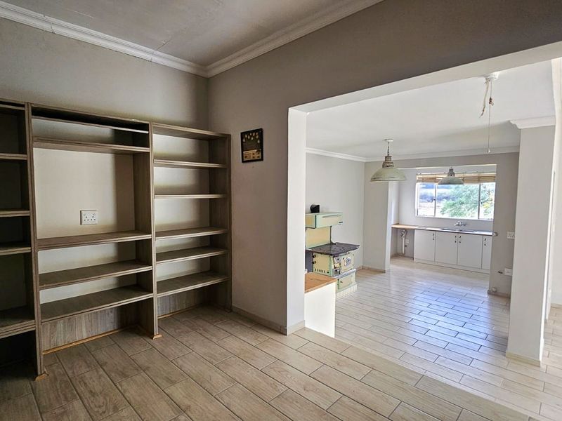 Open plan living and kitchen area featuring tiled flooring, built-in shelving, and a vintage stove, offering a functional layout with neutral wall finishes.