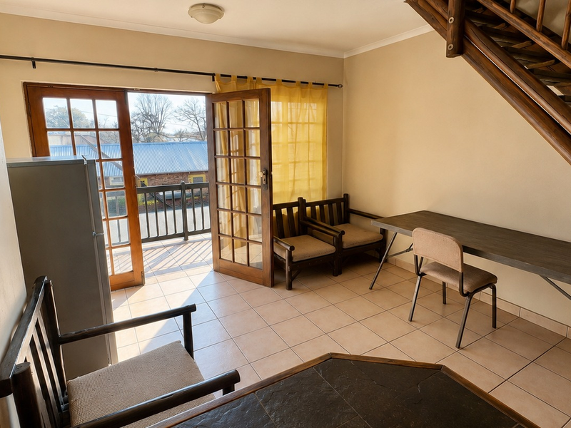 Living area featuring tiled flooring, a wooden staircase, and double glass doors providing direct access to an outdoor balcony.