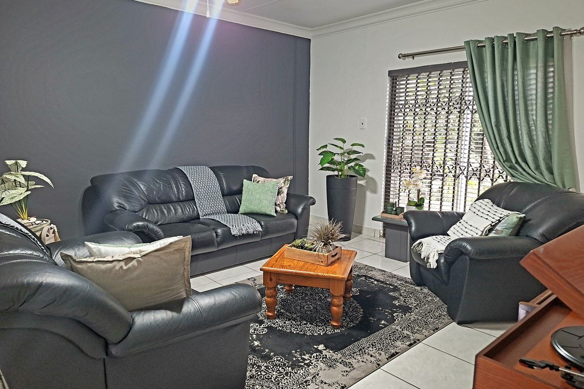 A comfortable living room featuring tiled flooring, a ceiling fan, and a security gate over the window, providing a functional and well-maintained space.