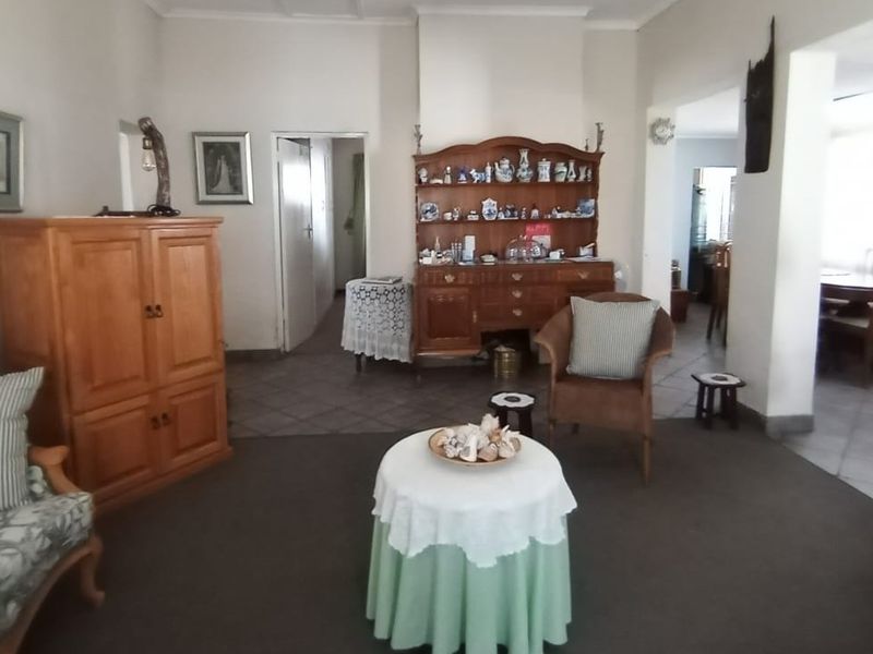 A spacious living area featuring a mix of carpet and tile flooring, with an open-plan layout leading into an adjacent dining space.