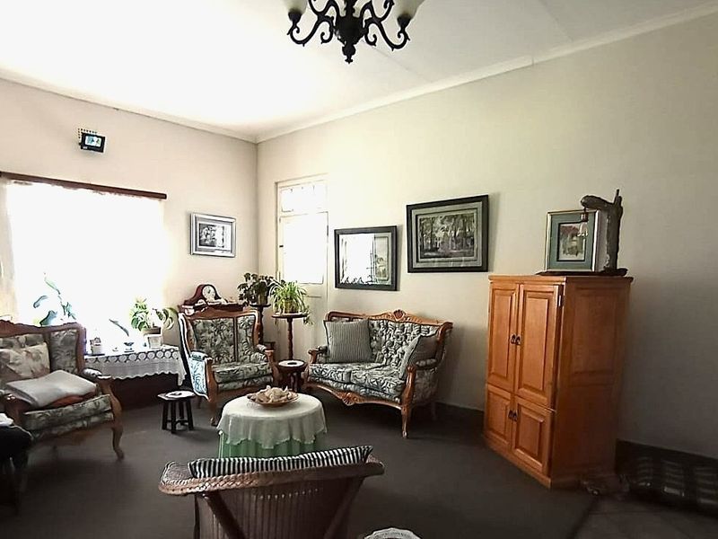 A spacious living room featuring neutral walls, a central light fixture, and large windows allowing for natural light.