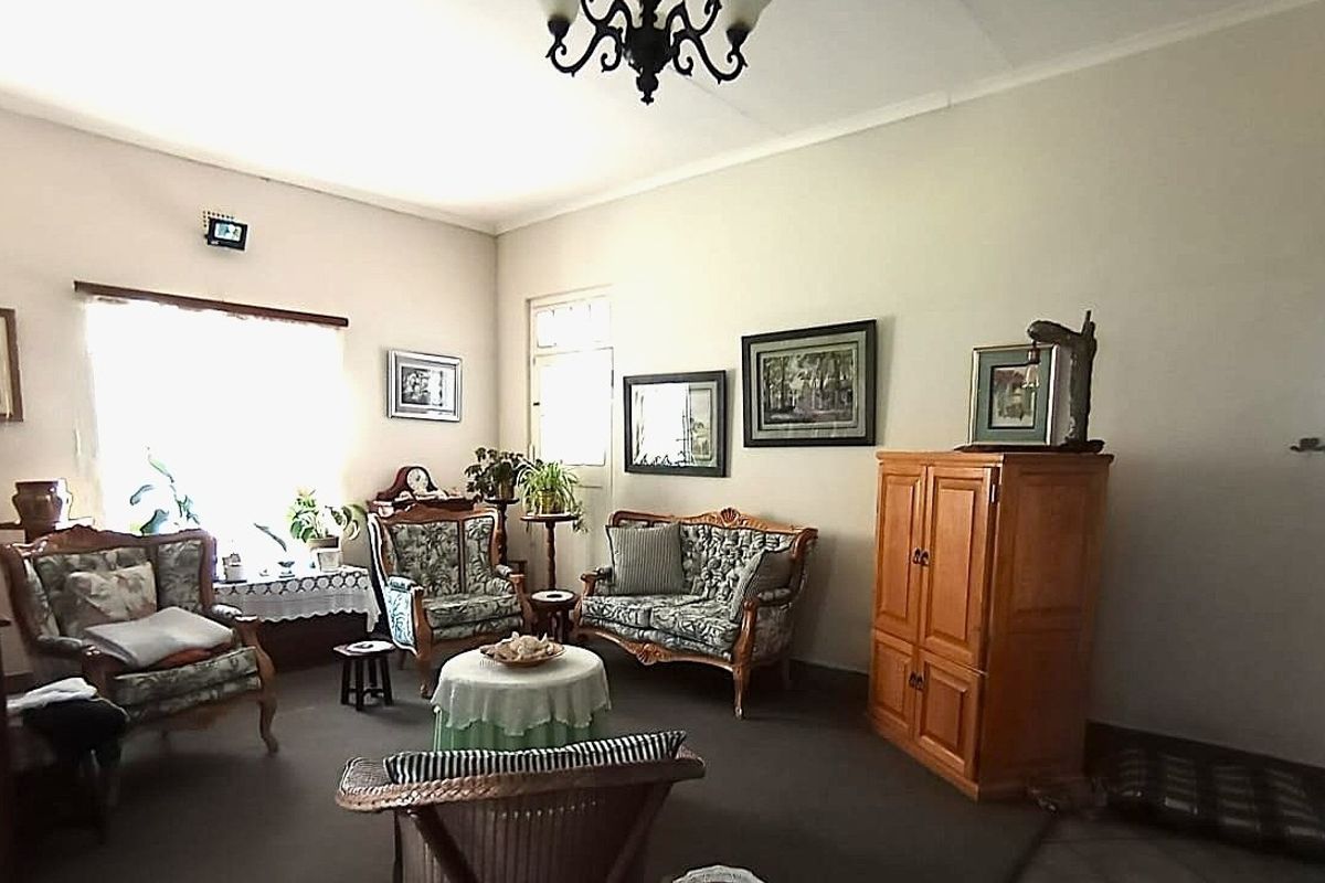 A spacious living room featuring neutral walls, a central light fixture, and large windows allowing for natural light.