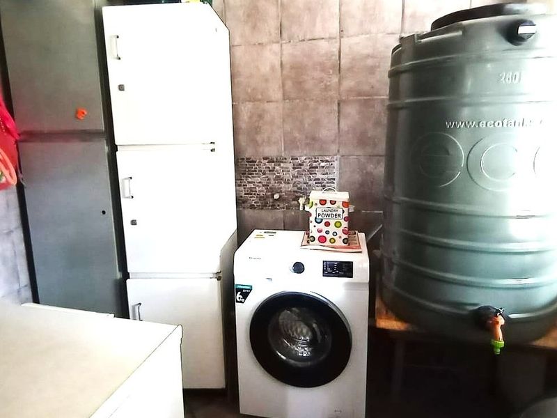 A functional laundry area featuring tiled walls and a large water storage tank, providing essential utility space for the home.