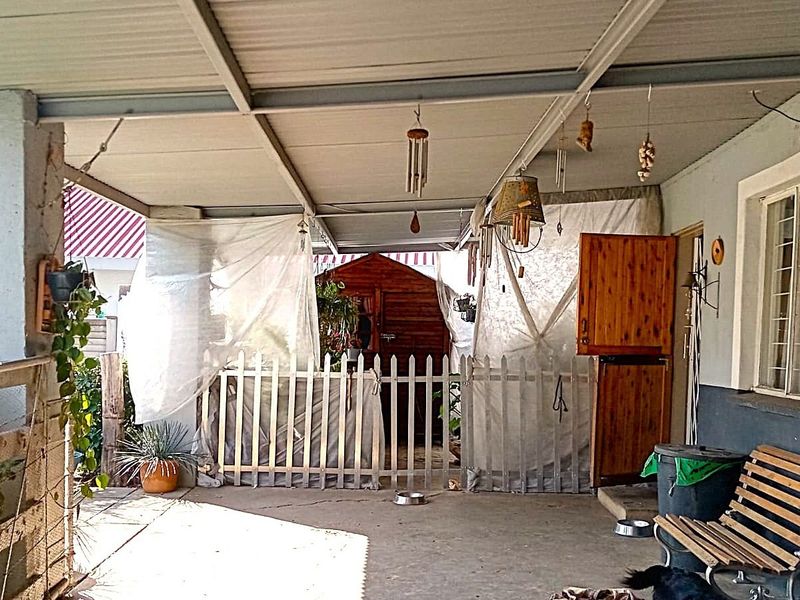 A covered outdoor patio area featuring a concrete floor, metal roofing, and a timber stable door, providing a functional space for outdoor living.