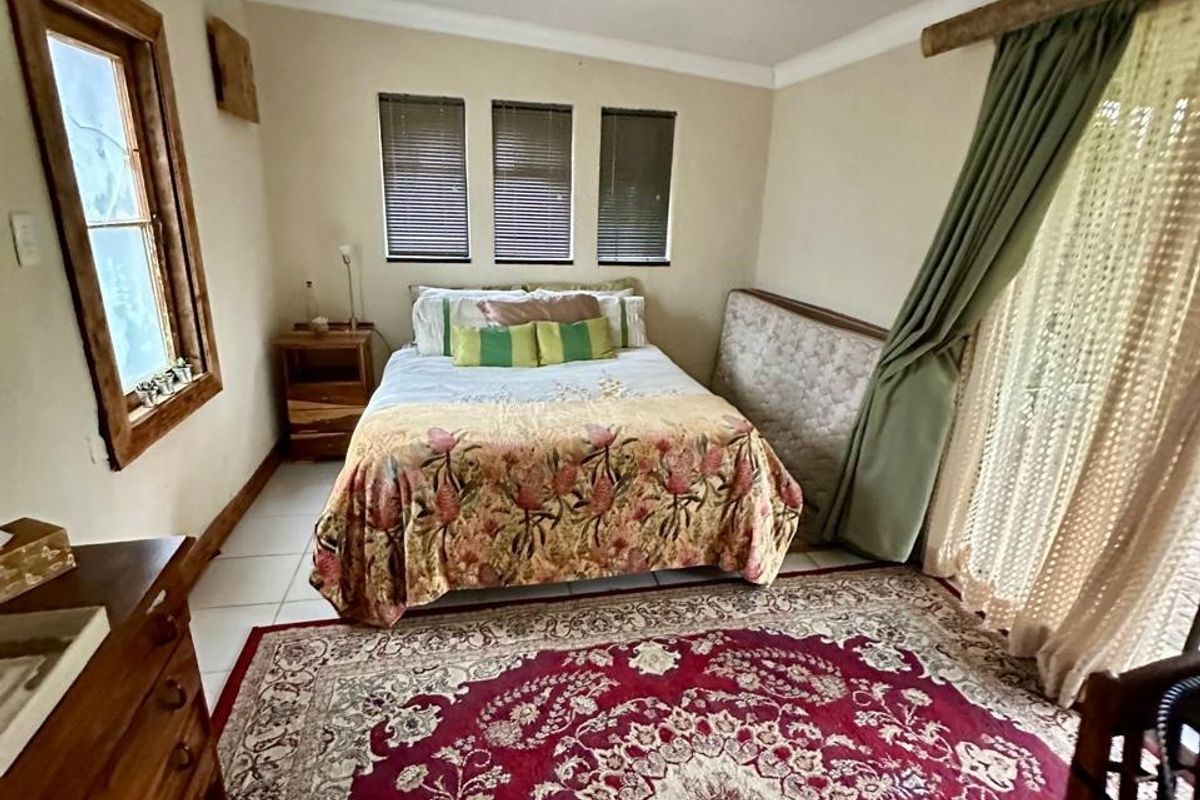 A bedroom featuring tiled flooring, timber-framed windows, and a sliding glass door providing access to the exterior.
