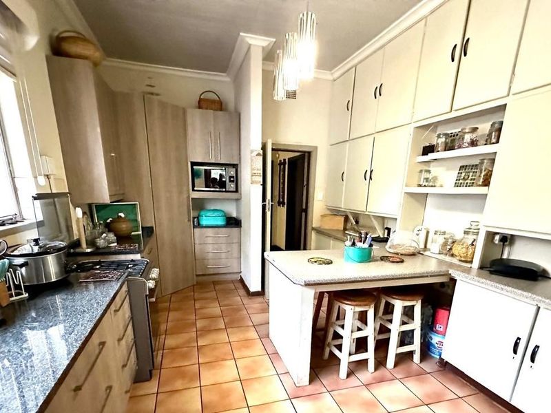 A functional kitchen featuring extensive built-in cabinetry, granite countertops, a gas stove, and a central breakfast nook with tiled flooring.
