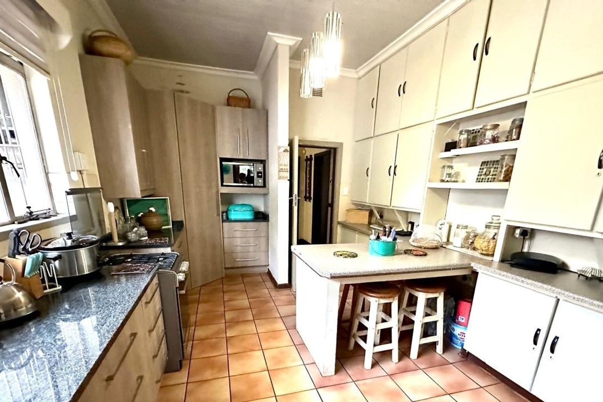 A functional kitchen featuring extensive built-in cabinetry, granite countertops, a gas stove, and a central breakfast nook with tiled flooring.