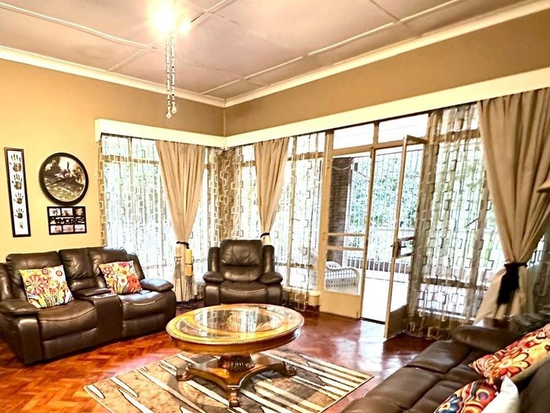 Spacious living room featuring classic parquet flooring, large windows with natural light, and direct access to an outdoor area through a security gate.