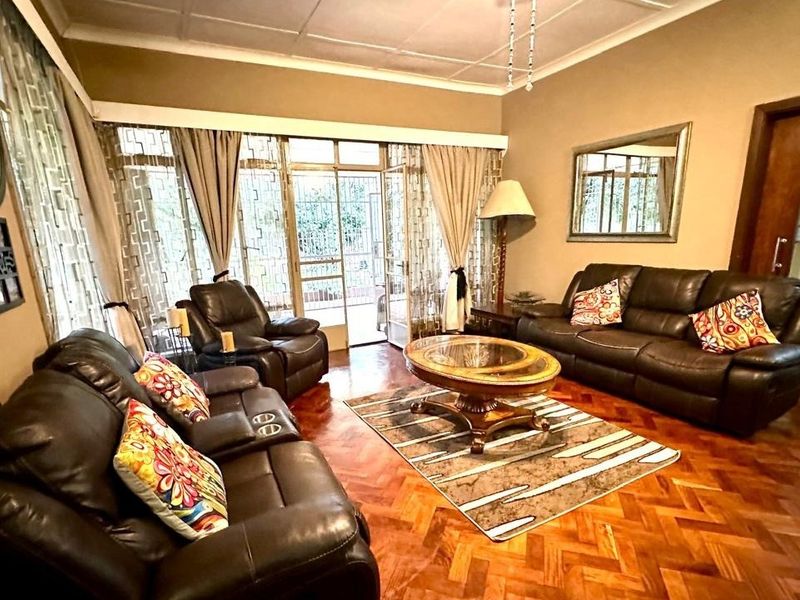 Spacious living room featuring classic parquet flooring, coved ceilings, and large glass sliding doors providing access to the outdoor area.