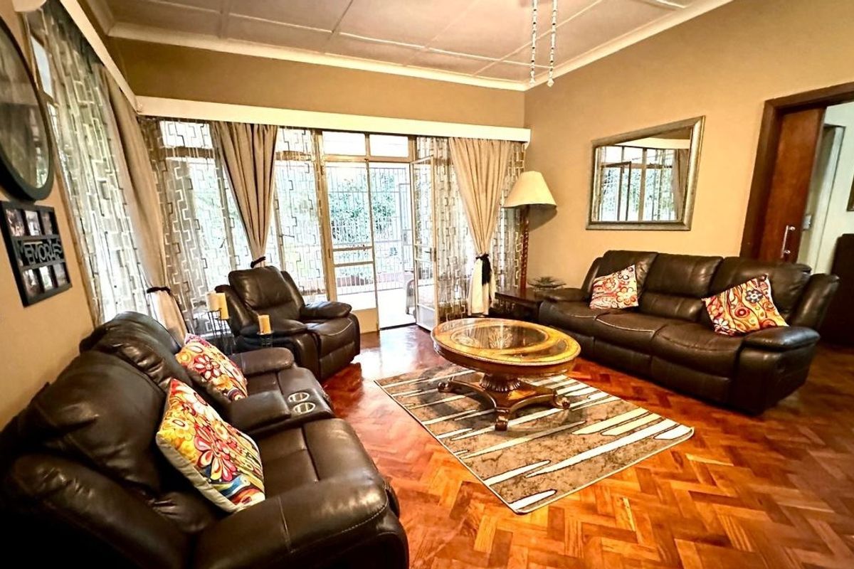 Spacious living room featuring classic parquet flooring, coved ceilings, and large glass sliding doors providing access to the outdoor area.