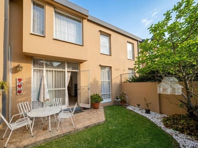 Rear view of the townhouse featuring a paved patio area, small private garden, and direct access to the interior through sliding glass doors.