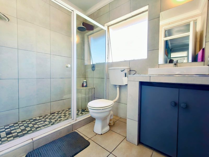 A functional bathroom featuring a tiled shower enclosure, a standard toilet, and a vanity unit with a basin.