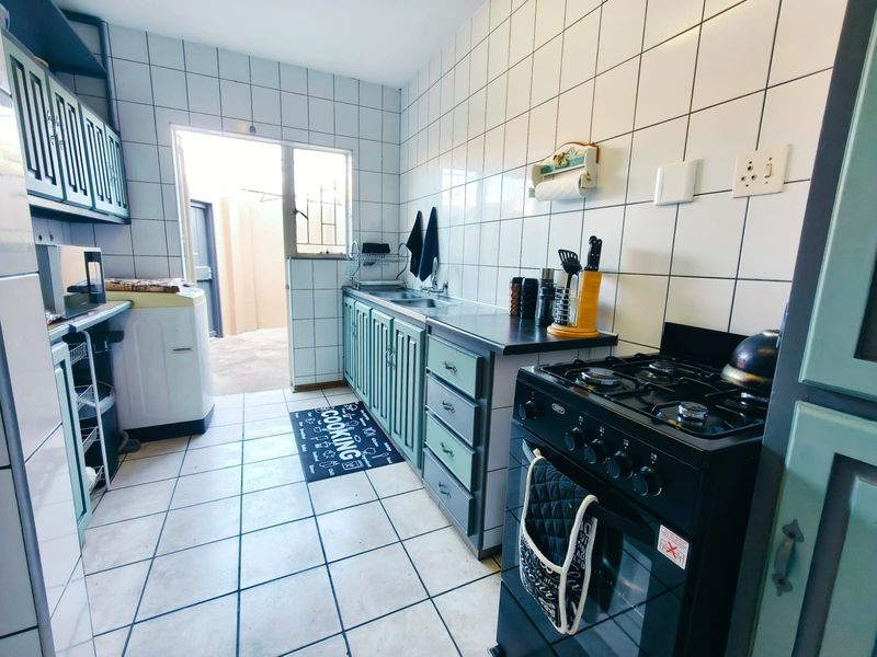 Functional kitchen featuring tiled splashbacks, built-in cabinetry, a gas stove, and direct access to an outdoor area.