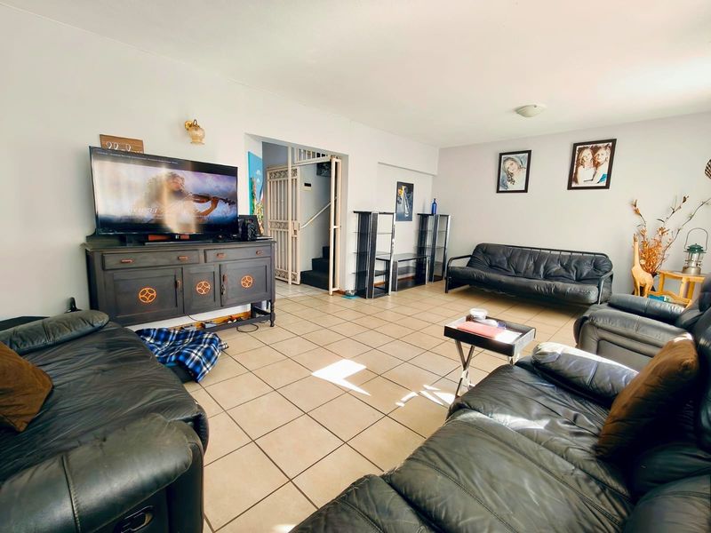 Spacious living room featuring neutral ceramic tile flooring and direct access to an internal staircase with a security gate.