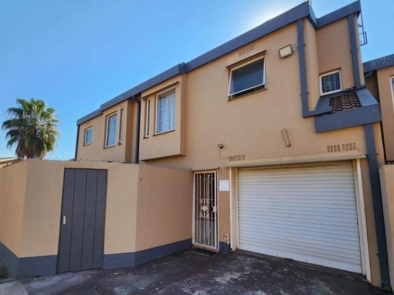 Front elevation of a townhouse featuring a single roller garage door, secure pedestrian entrance, and perimeter security spikes.