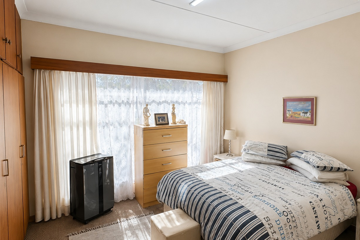 A well-lit bedroom featuring built-in wooden cupboards, neutral wall tones, and carpeted flooring, offering a comfortable and functional living space.