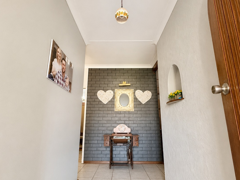 A bright hallway featuring a dark grey brick feature wall, tiled flooring, and a built-in recessed wall niche.
