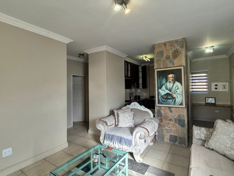 Open-plan living area featuring a stone-clad central pillar, tiled flooring, and integrated kitchen space with neutral wall finishes.