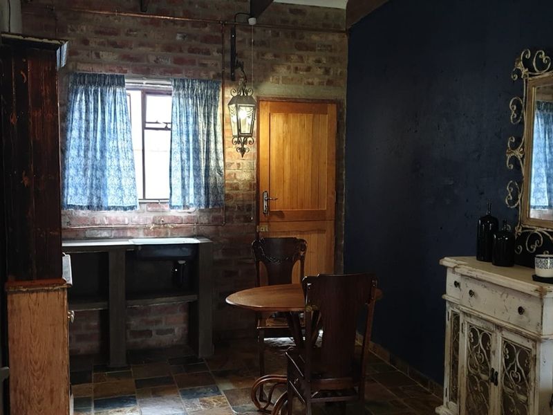 Rustic kitchen area featuring exposed brick walls, slate tile flooring, and a built-in concrete counter with a vintage aesthetic.