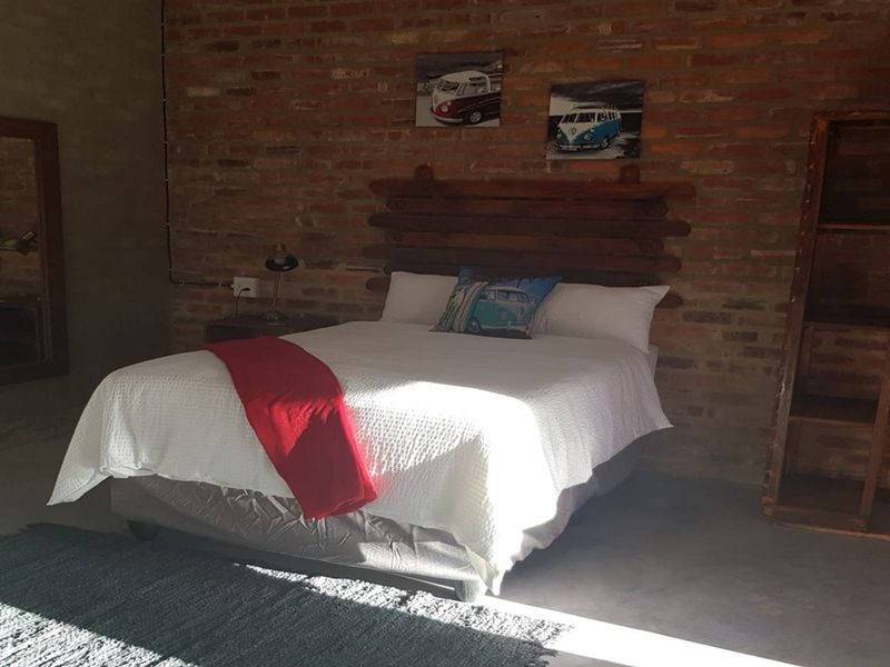A rustic bedroom featuring an exposed brick feature wall and polished concrete flooring, creating an industrial-style living space.